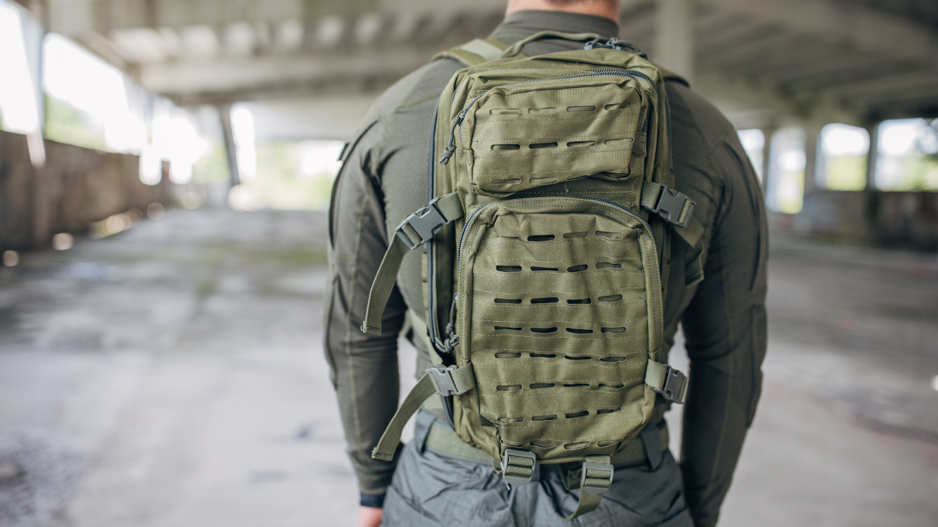 A man wearing a best tactical backpack walking in an abandoned warehouse in the background